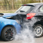 Two vehicles involved in a rear-end collision show significant damage and smoke at the crash scene, illustrating an uninsured motorist accident and insurance claim.