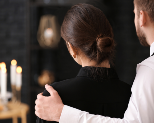 A grieving couple stands together at a funeral, illustrating the emotional impact of losing a loved one in a fatal workplace accident and the legal options available to families pursuing a wrongful death or third-party liability claim.