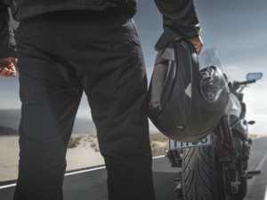 A man from the backside holding a motorcycle helmet.