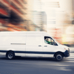White delivery van driving fast through city street