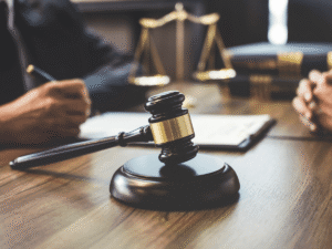 Close-up of a gavel on a desk with two people in discussion