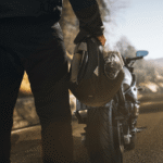 Motorcyclist holding helmet beside bike